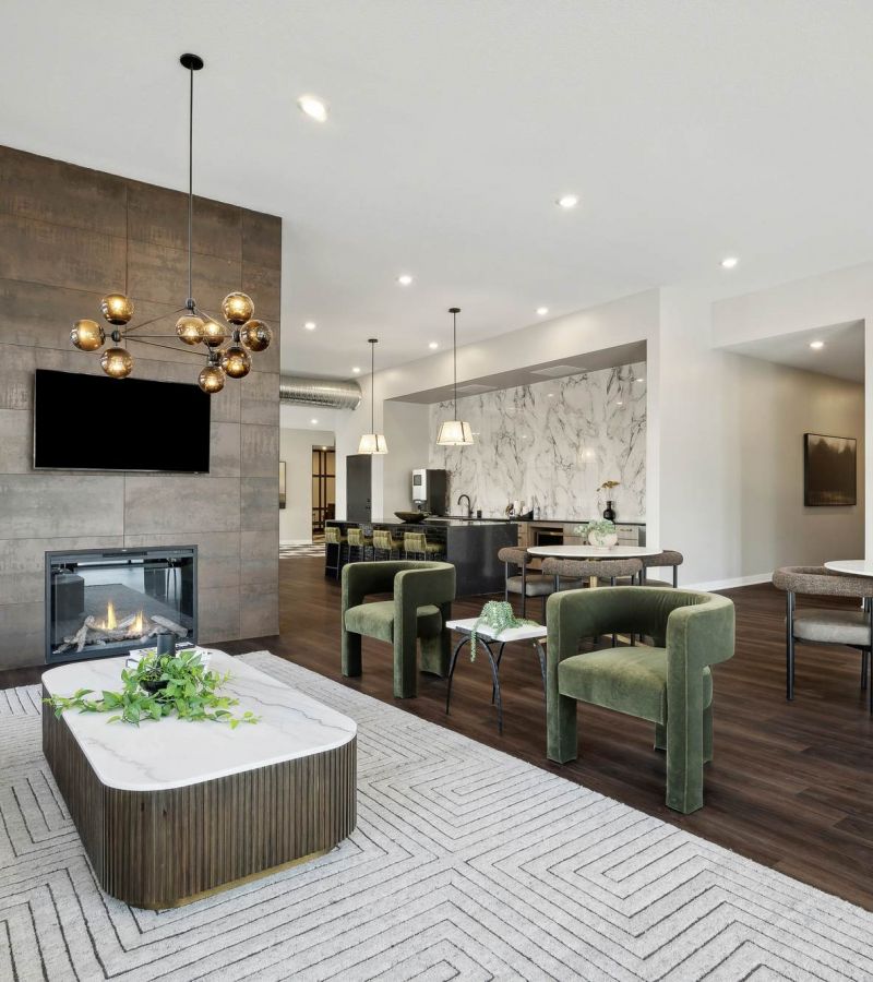 A stylish resident lounge at The Espen Residences in Oakdale, MN, featuring modern seating, a central coffee table, a fireplace with mounted TV, and contemporary lighting throughout the space.