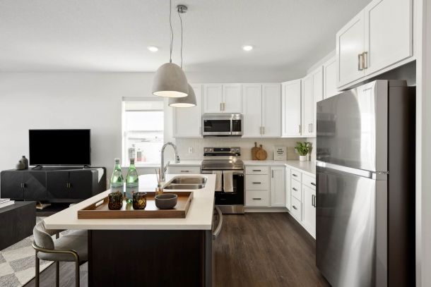 Modern kitchen with white cabinets, stainless steel appliances, and a central island with drinks on a tray.