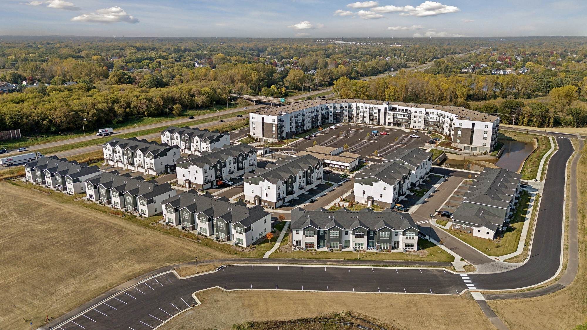 Aerial view of The Espen Residences surrounded by trees and roads under a partly cloudy sky.