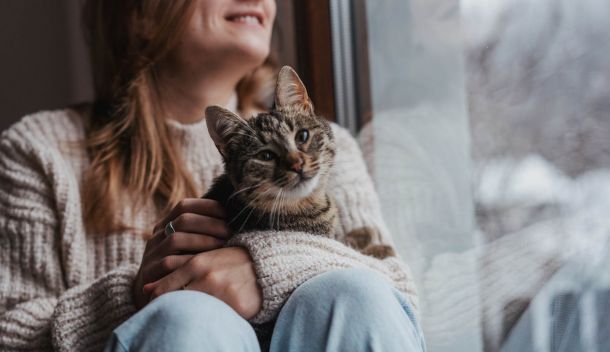 A resident holding a cat near a window at The Espen Residences in Oakdale, MN, highlighting the community’s pet-friendly living environment.