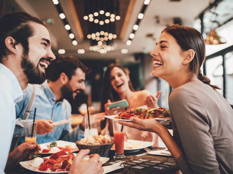 Friends enjoying a meal together at a local restaurant near The Espen Residences in Oakdale, MN, with warm lighting and a lively atmosphere.