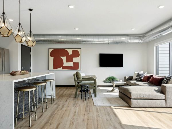 Modern open-plan living room and kitchen with neutral tones, geometric art, and industrial accents.