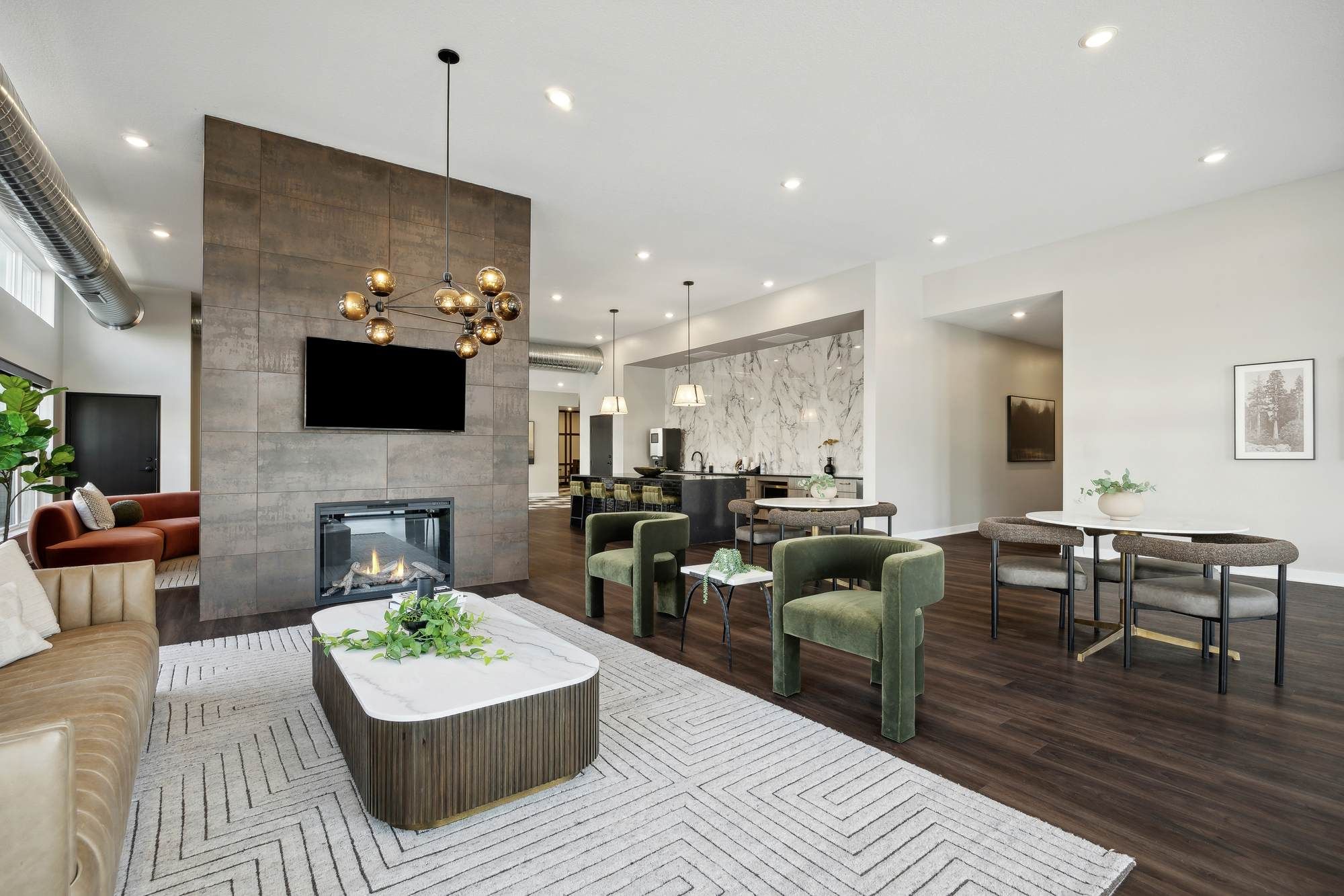 Modern living room with green chairs, a fireplace, TV, and dining area; neutral tones and stylish decor.