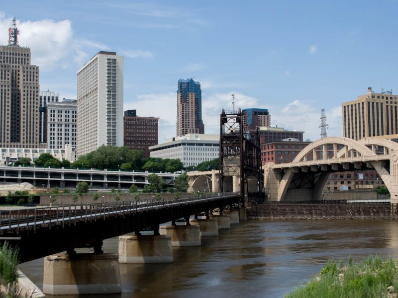 Downtown city skyline with tall buildings, a bridge, and a river under a partly cloudy sky near The Espen Residences