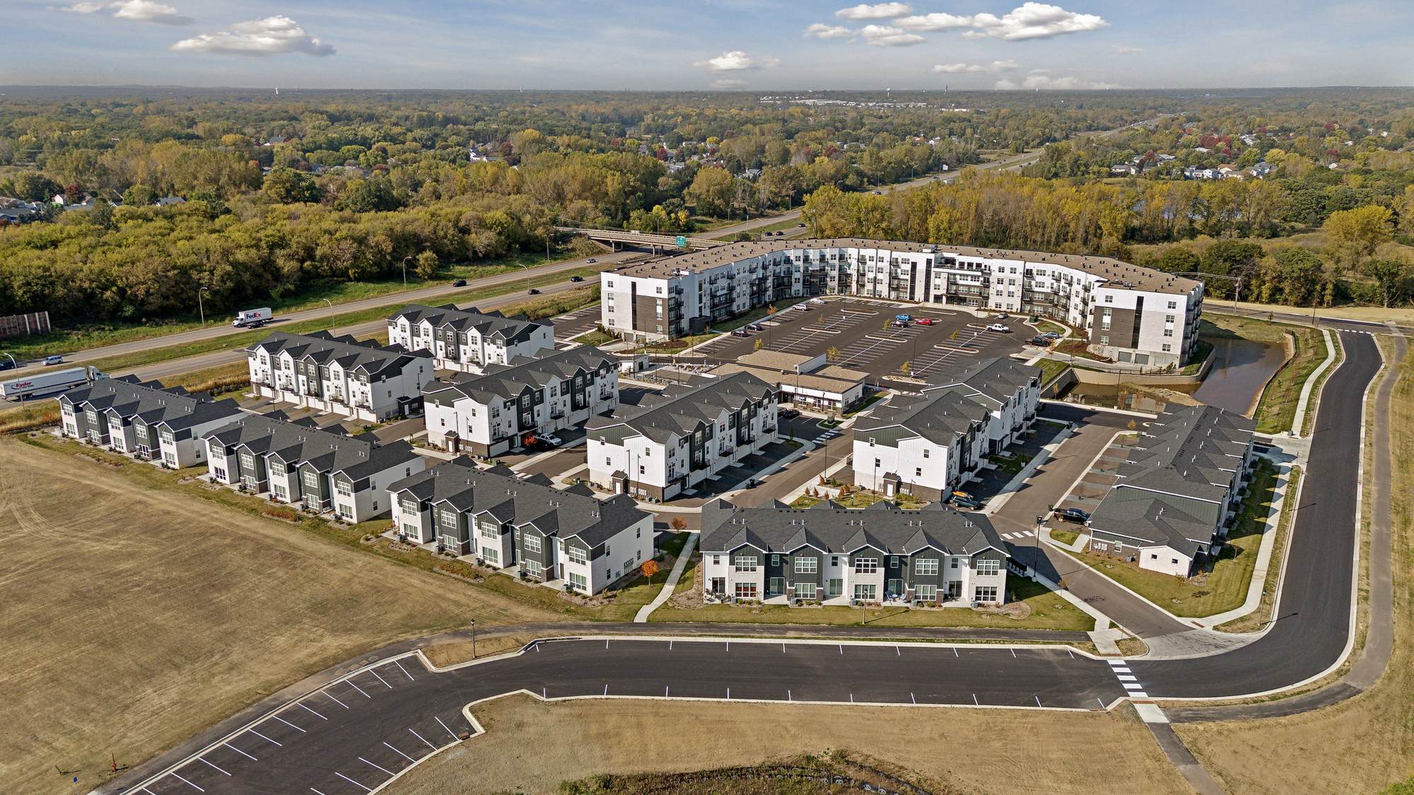 Aerial view of The Espen Residences surrounded by trees and roads under a partly cloudy sky.