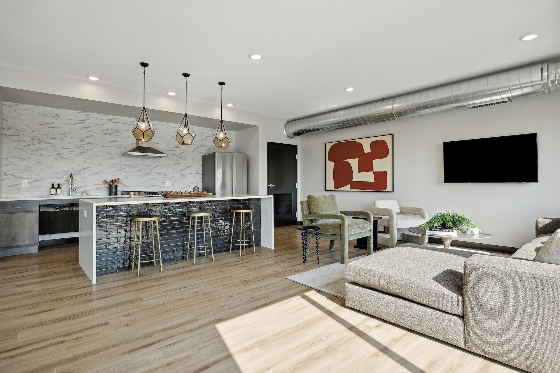 Modern skylounge at The Espen Residences in Oakdale, MN, featuring a spacious seating area, contemporary furnishings, a kitchen with island seating, pendant lighting, and stylish finishes.