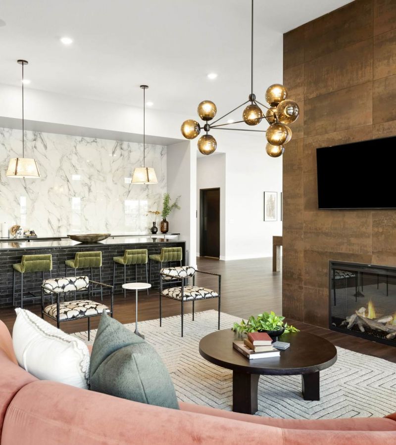 Modern open-concept living room and kitchen with a marble backsplash, green barstools, and a fireplace.